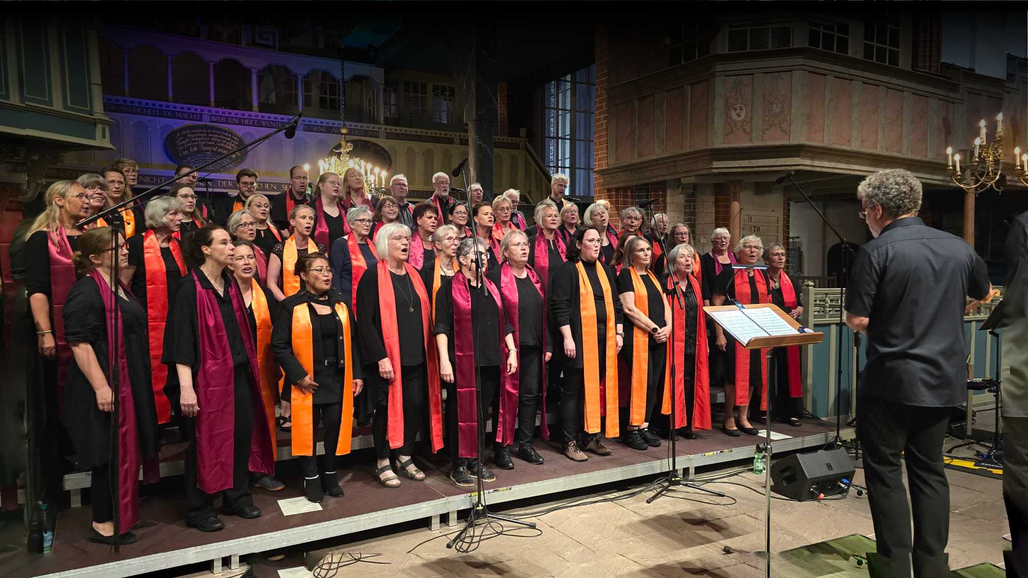 Der Ludgeri Gospelchor singt in der Ludgeri Kirche auf einem Podest stehend.